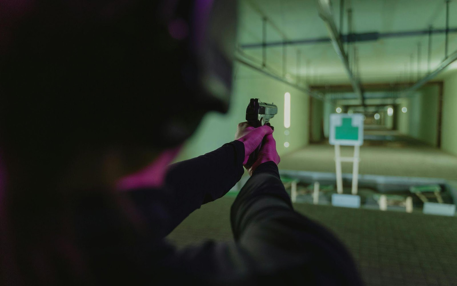 Person aiming a gun at a target.