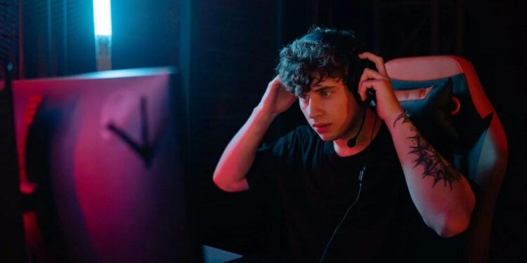Gamer wearing headphones in neon lighting.