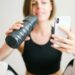 photo of woman holding white smartphone and sports bottle